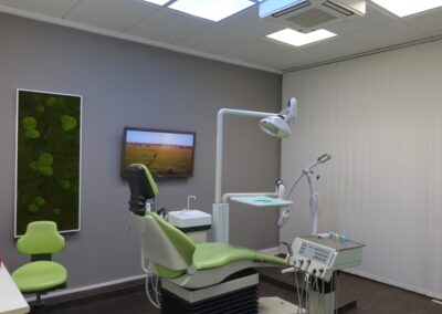 Moderner Behandlungsraum mit Moosbild und TV in der Zahnarztpraxis Dr. Pantas