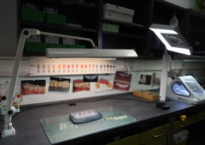 Dentallabor-Arbeitsplatz mit Farbmustern und Zahnfotos bei Dr. Pantas